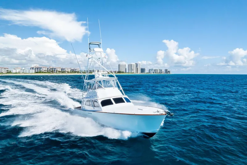 Nic-nac Yacht Photos Pics 1977 Merritt Sportfish yacht cruising on blue ocean near city skyline.