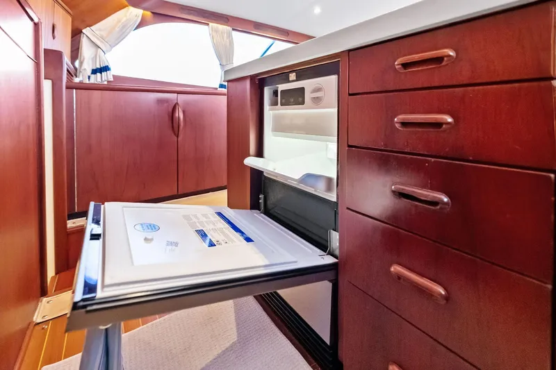 Nic-nac Yacht Photos Pics 1977 Merritt Sportfish interior with open fridge and wooden cabinetry.