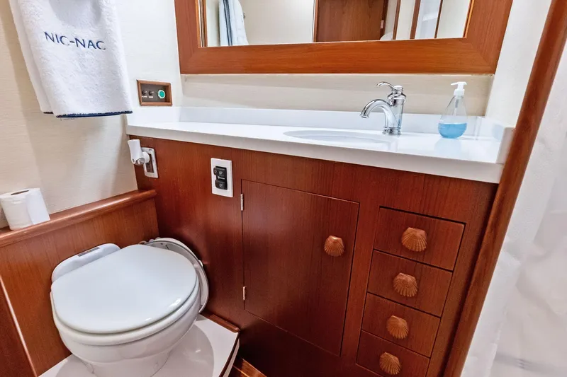 Nic-nac Yacht Photos Pics 1977 Merritt Sportfish bathroom with wooden cabinetry, sink, and toilet.