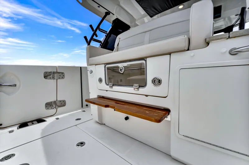  Yacht Photos Pics 2023 Boston Whaler 350 Realm interior, featuring sleek seating and storage against a clear blue sky.