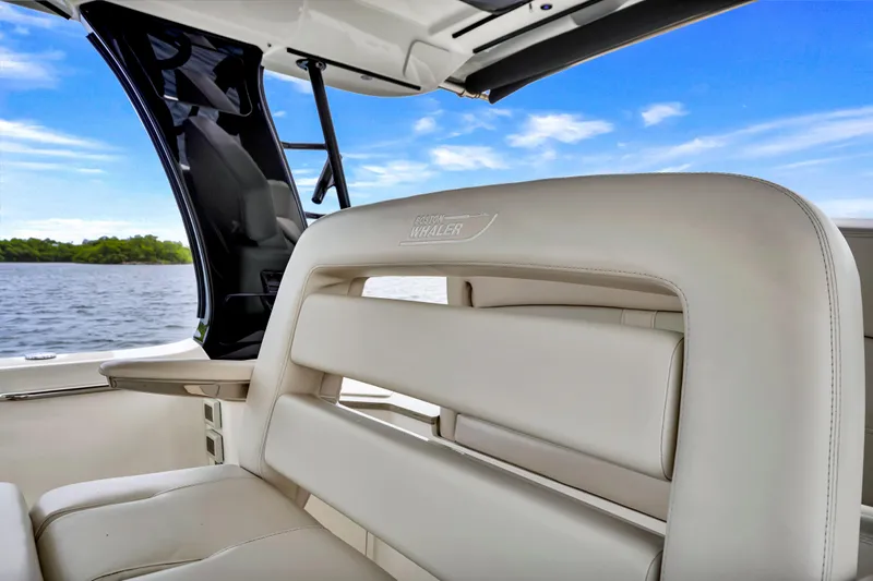  Yacht Photos Pics 2023 Boston Whaler 350 Realm interior with luxurious seating, overlooking serene water and blue sky.
