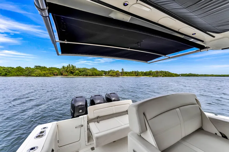  Yacht Photos Pics 2023 Boston Whaler 350 Realm boat with triple engines, scenic water view, and retractable sunshade.