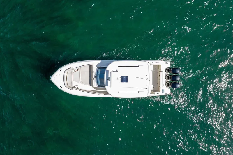  Yacht Photos Pics Aerial view of 2023 Boston Whaler 350 Realm boat on clear green water.