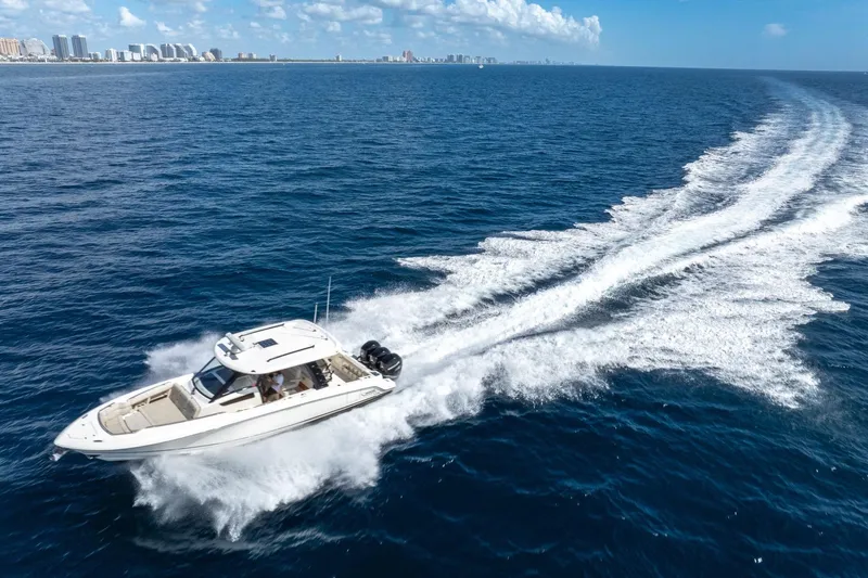  Yacht Photos Pics 2023 Boston Whaler 350 Realm cruising on open ocean with city skyline in background.