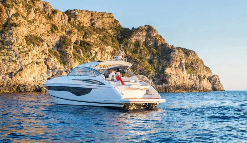  Yacht Photos Pics Luxury 2025 Princess V40 yacht cruising near rocky coastline at sunset.