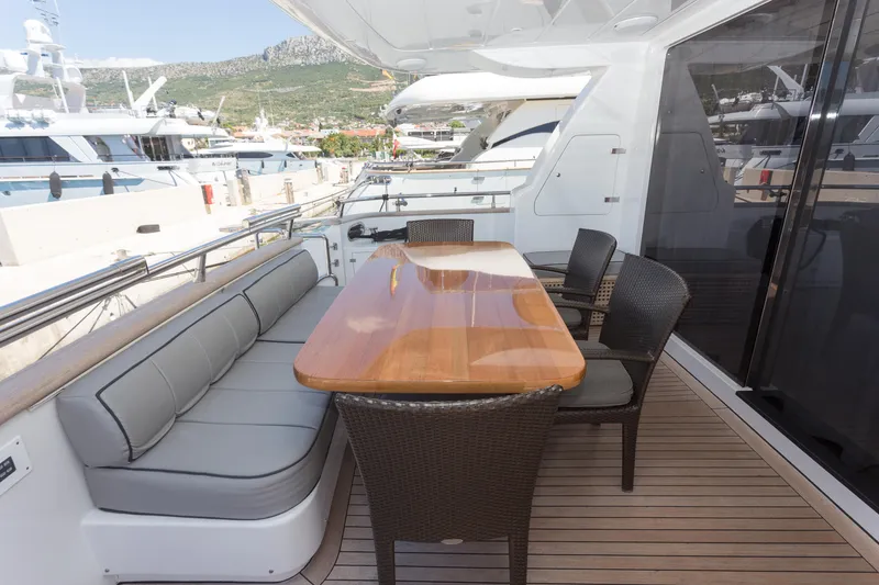  Yacht Photos Pics Outdoor dining area on 2008 Maiora 20S yacht with wooden table and cushioned seating.