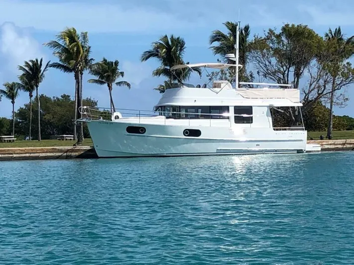  Yacht Photos Pics 2019 Beneteau Swift Trawler 44 docked by palm trees in a serene waterway.