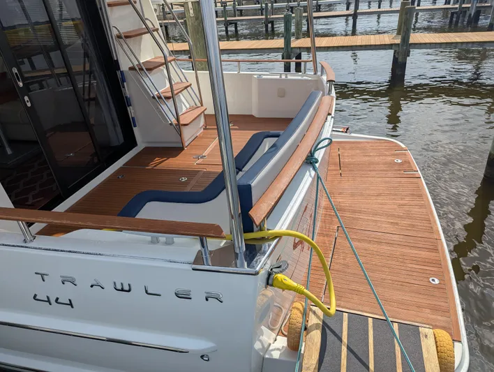  Yacht Photos Pics 2019 Beneteau Swift Trawler 44 docked, showcasing elegant wooden deck and seating area.