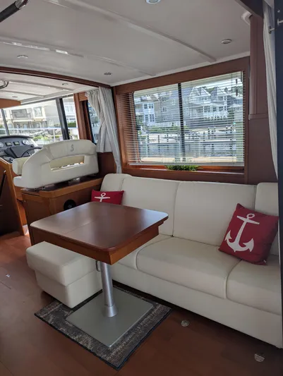  Yacht Photos Pics Interior of 2019 Beneteau Swift Trawler 44 with white sofa and wooden table.