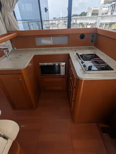  Yacht Photos Pics 2019 Beneteau Swift Trawler 44 kitchen with stove, microwave, and wooden cabinetry.