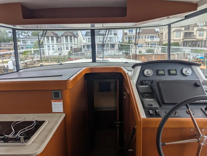  Yacht Photos Pics Interior view of 2019 Beneteau Swift Trawler 44 helm with navigation controls and steering wheel.