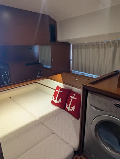  Yacht Photos Pics Cozy cabin interior of 2019 Beneteau Swift Trawler 44 with bed, anchor pillows, and washer.