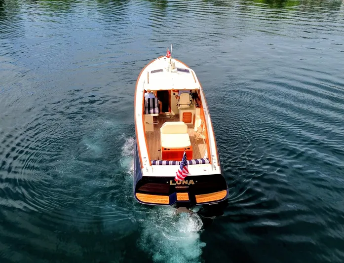 Luna Yacht Photos Pics Hinckley Picnic Boat 2000 cruising on calm water, rear view with American flag.