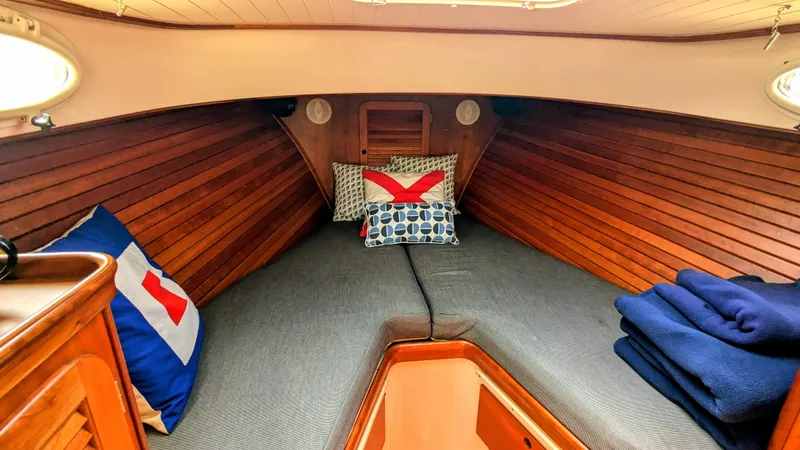 Luna Yacht Photos Pics Cozy cabin interior of 2000 Hinckley Picnic Boat with wooden paneling and nautical-themed pillows.