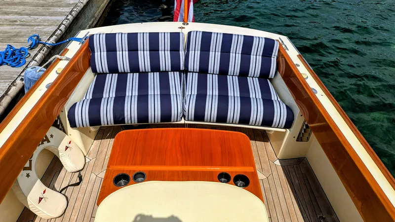Luna Yacht Photos Pics 2000 Hinckley Picnic Boat interior with striped seating and wooden table by the water.