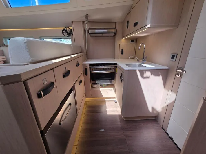 Yachting Conseil Yacht Photos Pics Modern kitchen interior of 2023 Jeanneau 60 yacht with sleek cabinetry and appliances.