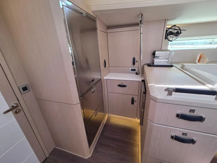 Yachting Conseil Yacht Photos Pics Modern kitchen interior of 2023 Jeanneau 60 yacht with sleek cabinetry and appliances.