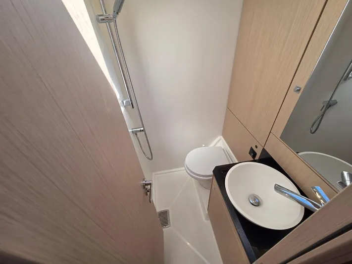 Yachting Conseil Yacht Photos Pics 2023 Jeanneau 60 yacht bathroom with modern sink, shower, and wooden cabinetry.
