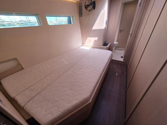 Yachting Conseil Yacht Photos Pics 2023 Jeanneau 60 yacht cabin with bed, windows, and modern interior design.