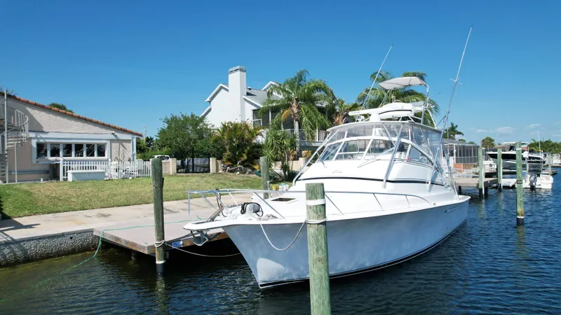 The Boo Factor Yacht Photos Pics 2003 Ocean 40 Super Sport yacht docked by waterfront homes under clear blue sky.