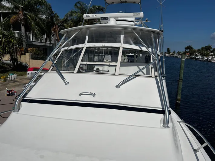 The Boo Factor Yacht Photos Pics 2003 Ocean 40 Super Sport boat docked by waterfront homes, clear sky.