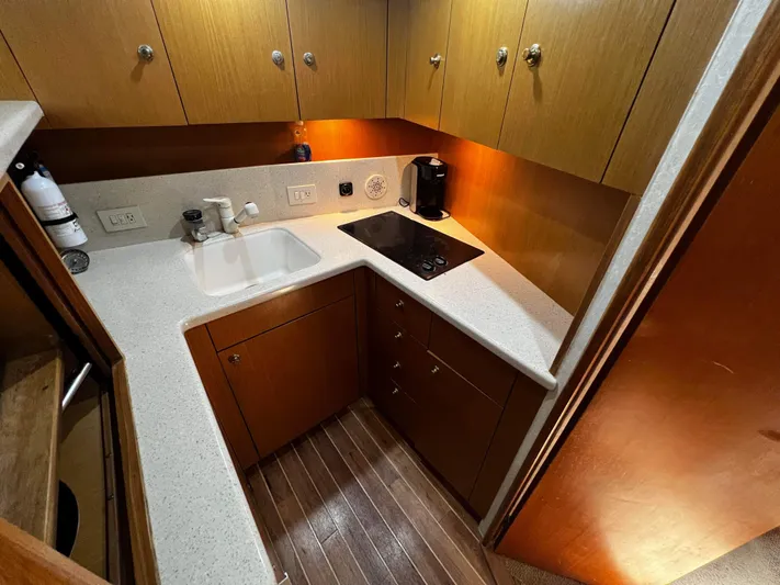 The Boo Factor Yacht Photos Pics Compact kitchen in 2003 Ocean 40 Super Sport yacht with sink, stove, and wooden cabinets.