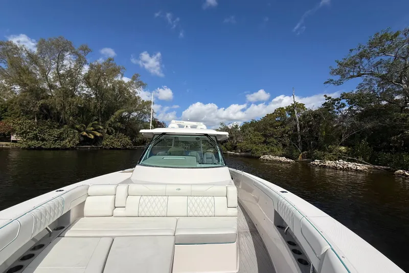  Yacht Photos Pics 2020 Regal 38 SAV boat cruising on a scenic river under a clear blue sky.