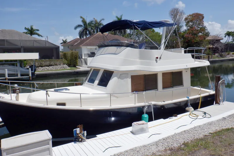 Betty Sue Yacht Photos Pics 2006 Mainship 34 Trawler docked in a sunny marina, surrounded by palm trees.