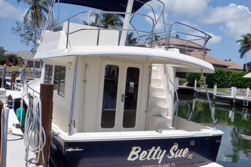 Betty Sue Yacht Photos Pics 2006 Mainship 34 Trawler docked, featuring rear view with stairs and tropical surroundings.