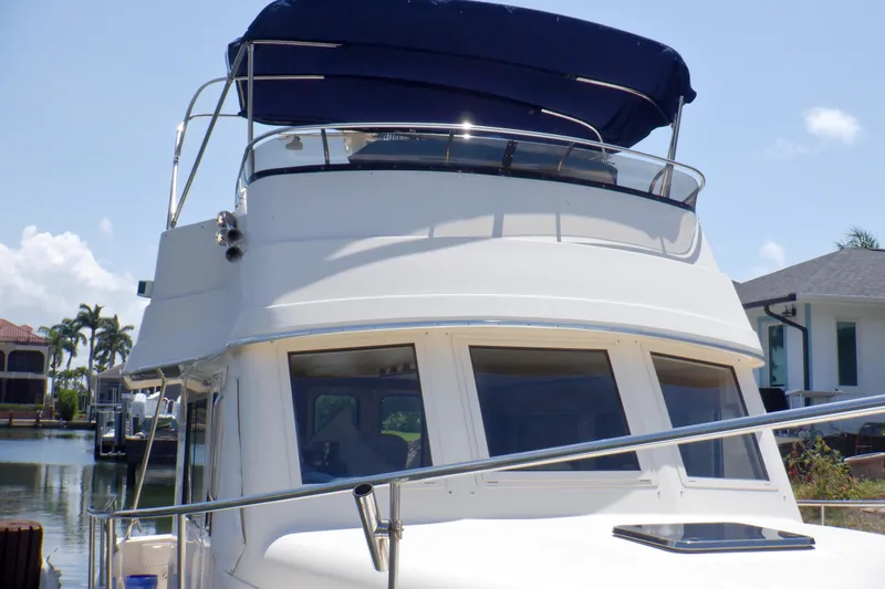Betty Sue Yacht Photos Pics 2006 Mainship 34 Trawler with blue canopy, docked near waterfront homes.