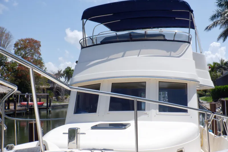 Betty Sue Yacht Photos Pics 2006 Mainship 34 Trawler with blue canopy, docked near palm trees.