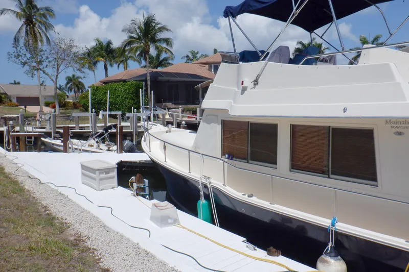 Betty Sue Yacht Photos Pics 2006 Mainship 34 Trawler docked, surrounded by palm trees and waterfront homes.