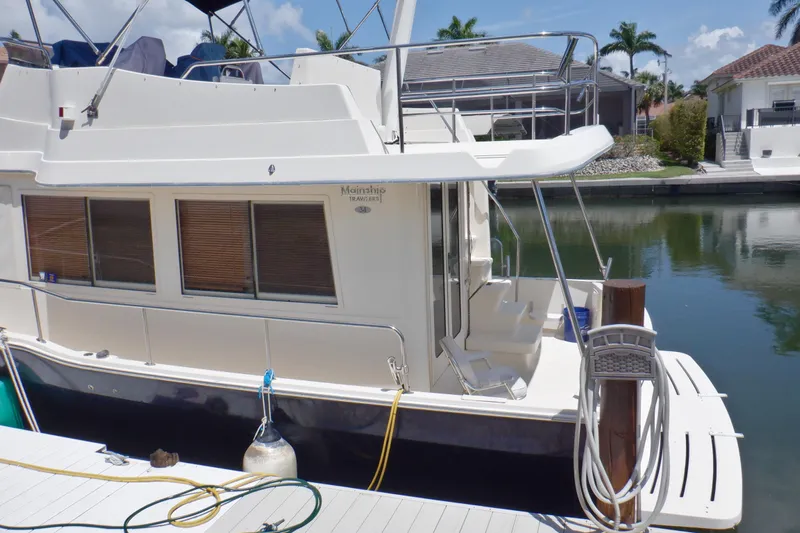 Betty Sue Yacht Photos Pics 2006 Mainship 34 Trawler docked by a canal, featuring spacious deck and windows.