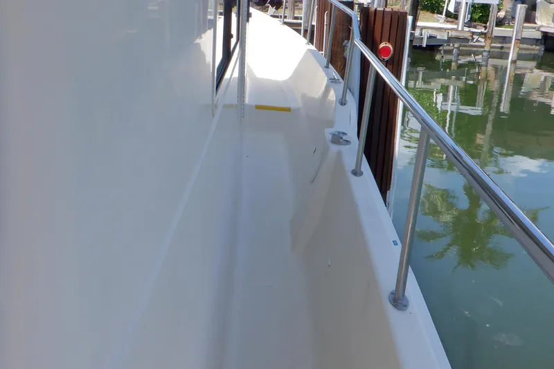 Betty Sue Yacht Photos Pics 2006 Mainship 34 Trawler side deck with railing, docked by calm water.