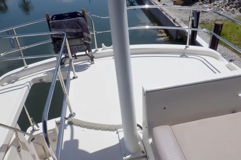 Betty Sue Yacht Photos Pics 2006 Mainship 34 Trawler deck with railing and seating, docked by calm water.