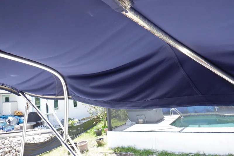 Betty Sue Yacht Photos Pics Blue canopy on a 2006 Mainship 34 Trawler, near a poolside setting.