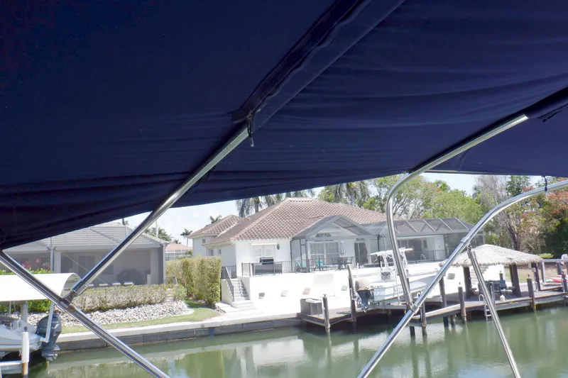 Betty Sue Yacht Photos Pics 2006 Mainship 34 Trawler with blue canopy, docked near waterfront homes.