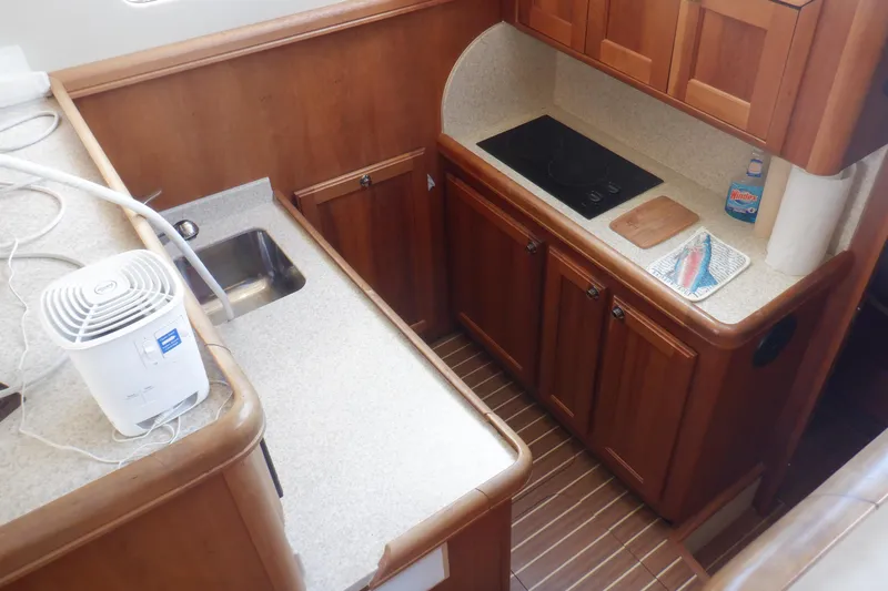 Betty Sue Yacht Photos Pics 2006 Mainship 34 Trawler kitchen with wooden cabinets, sink, and stovetop.