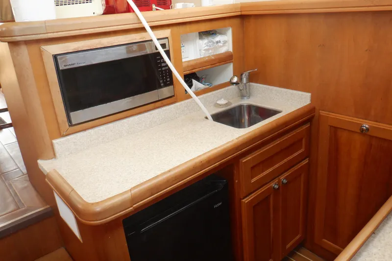 Betty Sue Yacht Photos Pics 2006 Mainship 34 Trawler galley with microwave, sink, and wooden cabinetry.