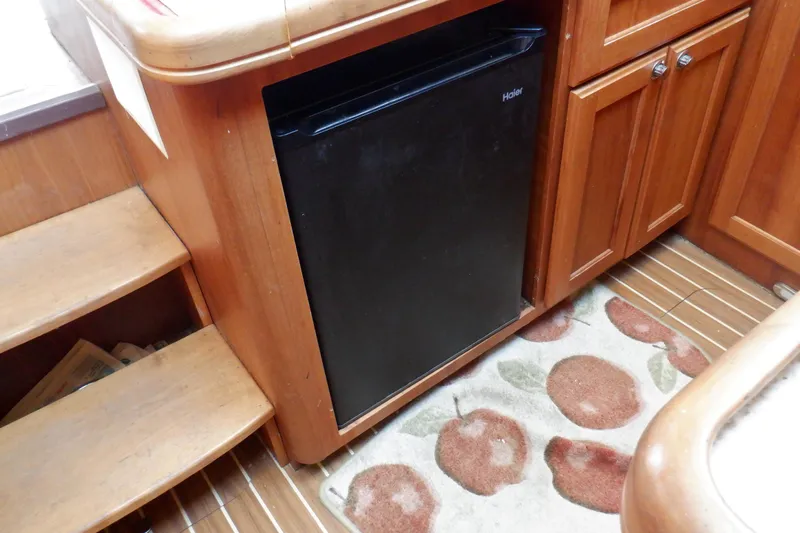 Betty Sue Yacht Photos Pics 2006 Mainship 34 Trawler interior with wooden cabinetry and compact black fridge.