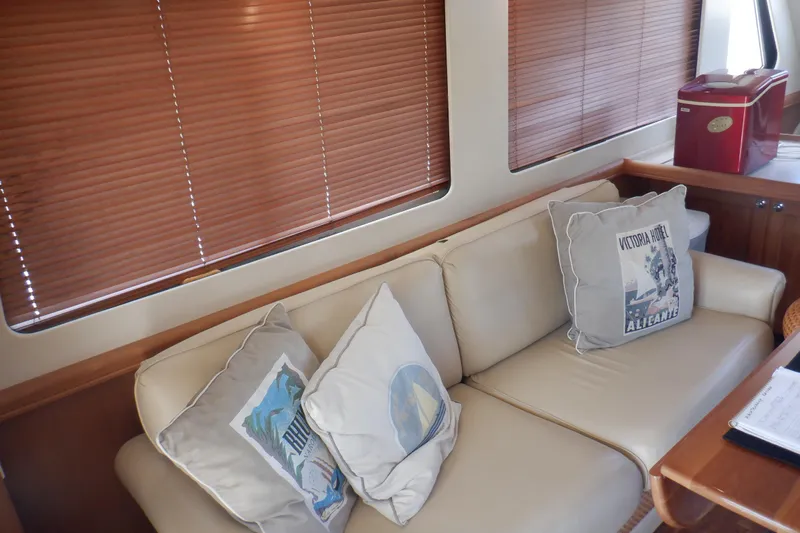 Betty Sue Yacht Photos Pics Interior of 2006 Mainship 34 Trawler with beige sofa and decorative pillows.