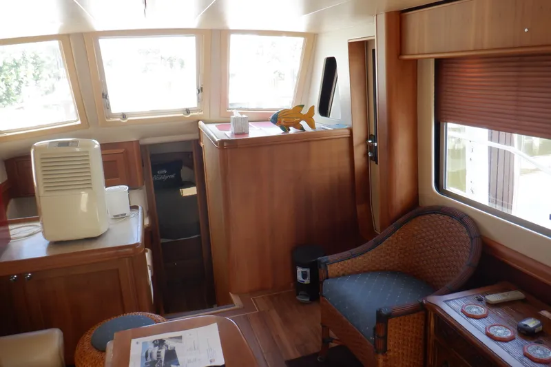 Betty Sue Yacht Photos Pics Interior of 2006 Mainship 34 Trawler with wooden furnishings and wicker chair.