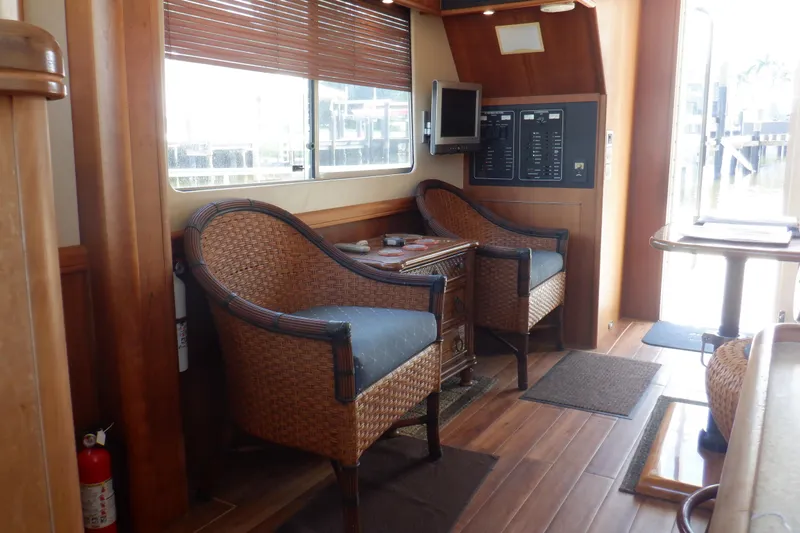 Betty Sue Yacht Photos Pics Interior of 2006 Mainship 34 Trawler with wicker chairs and wooden flooring.