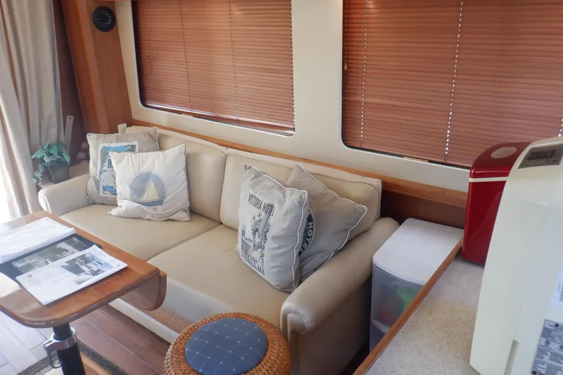 Betty Sue Yacht Photos Pics Interior of 2006 Mainship 34 Trawler with beige sofa, nautical pillows, and wooden accents.