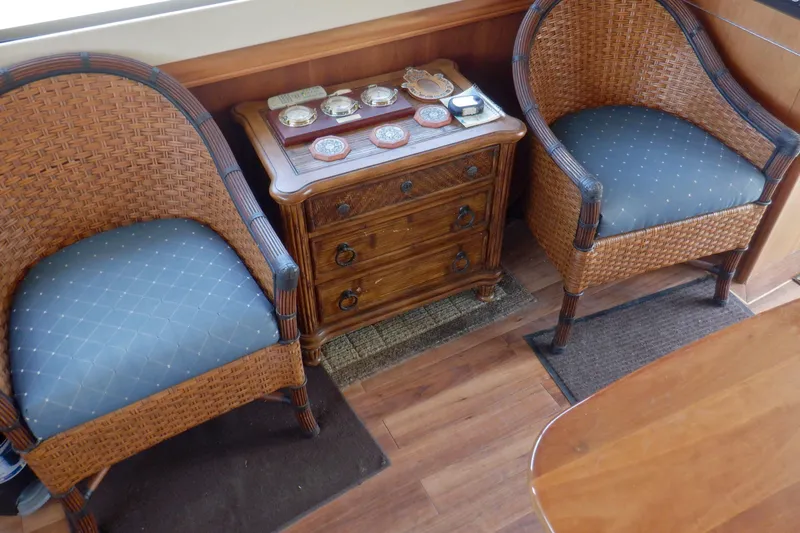 Betty Sue Yacht Photos Pics Interior of 2006 Mainship 34 Trawler with wicker chairs and wooden cabinet.