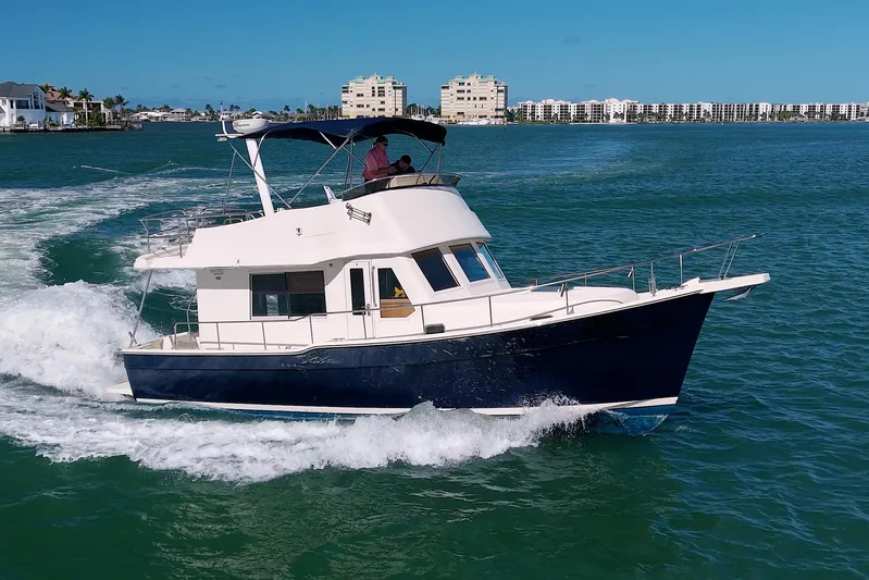 Betty Sue Yacht Photos Pics 2006 Mainship 34 Trawler cruising on blue ocean near coastal buildings.