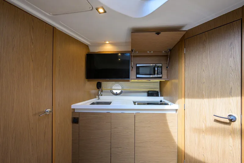 Yacht Photos Pics Modern kitchen interior of 2015 Beneteau 38 GT yacht with wood finish and appliances.