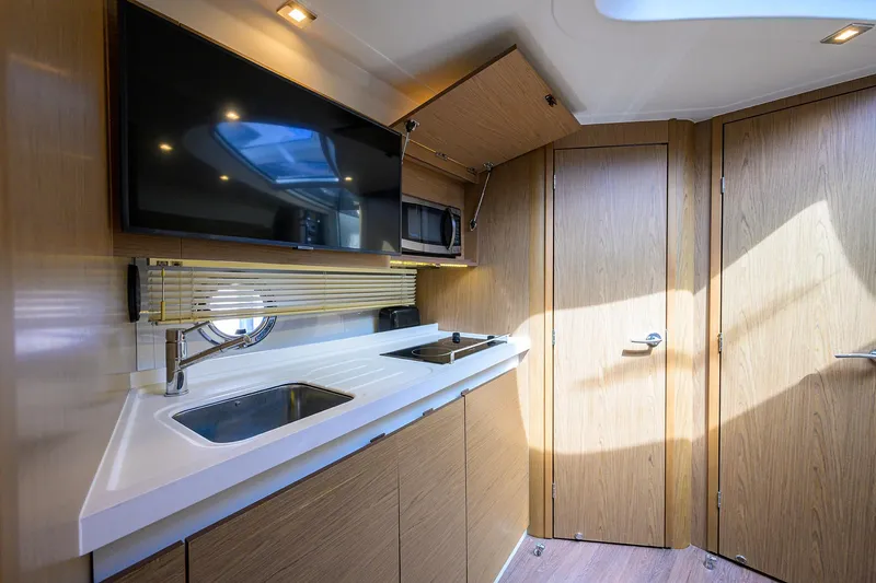  Yacht Photos Pics Modern kitchen interior of 2015 Beneteau 38 GT yacht with wood finish and appliances.