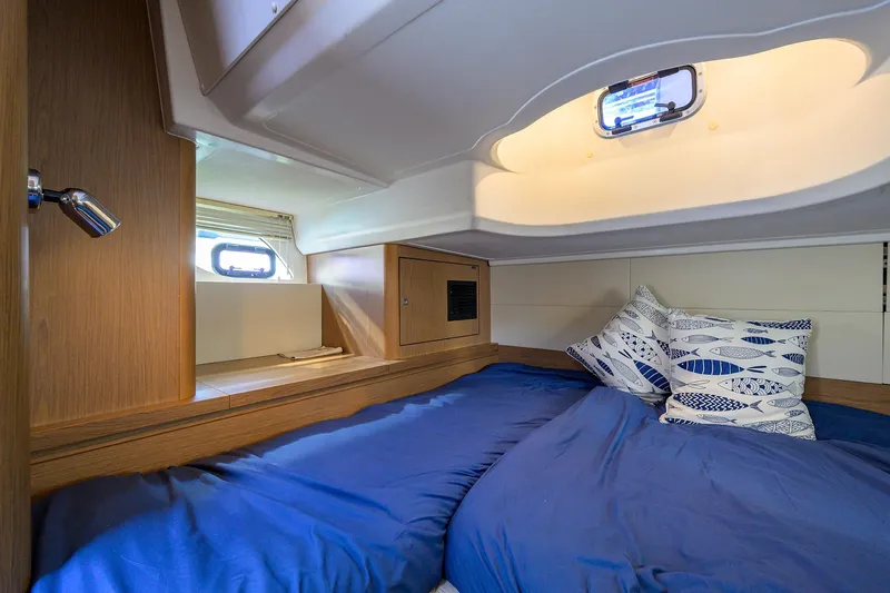  Yacht Photos Pics Cozy cabin interior of 2015 Beneteau 38 GT yacht with blue bedding and porthole windows.