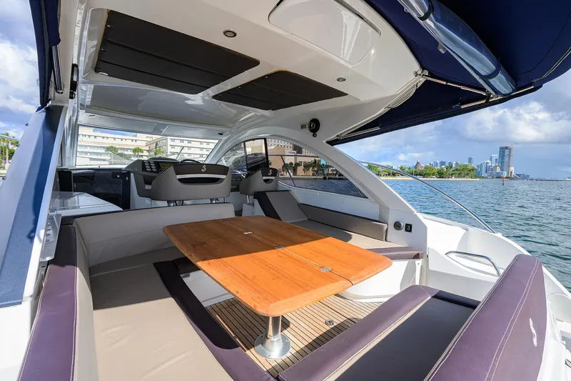  Yacht Photos Pics 2015 Beneteau 38 GT yacht interior with seating and table, overlooking waterfront skyline.